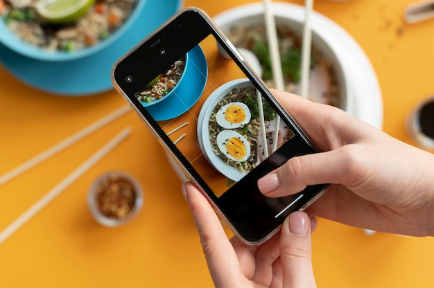 Woman taking photo of a bowl of ramen