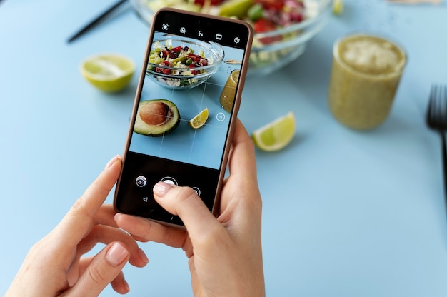 Woman taking photo of a bowl with salad and half of avocado