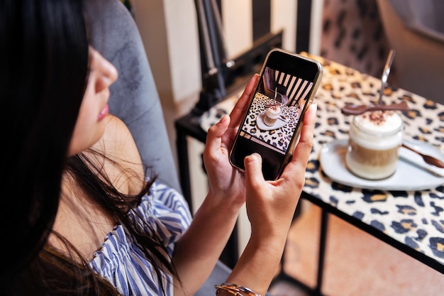 Woman taking a photo of her coffee with her phone