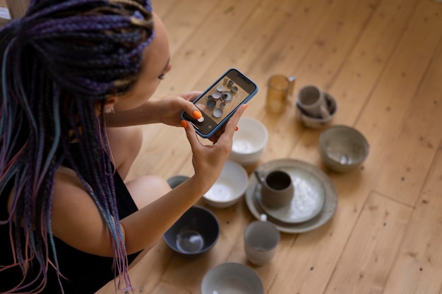 Woman taking photos of ceramic kitchenware at home