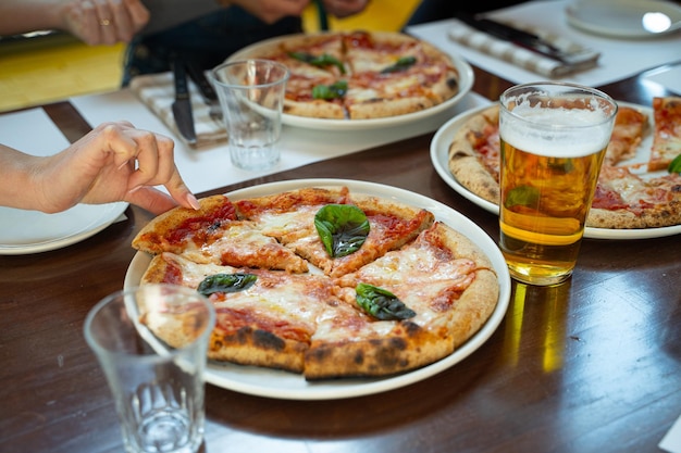 Photo woman taking slice of pizza from plate with beer nearby