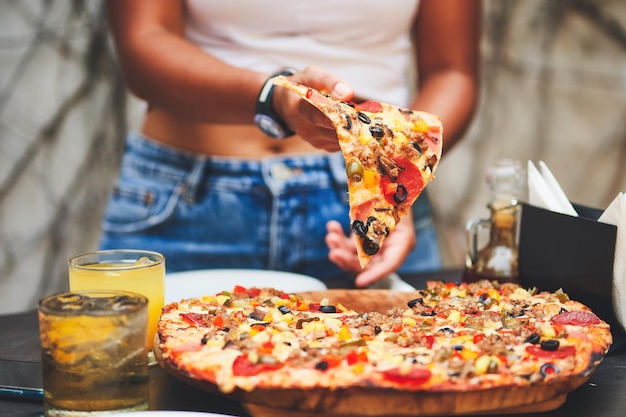 woman taking a slice of pizza with her hand