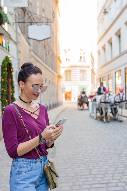 Woman talk by her smartphone in city. Young attractive tourist outdoors in italian city