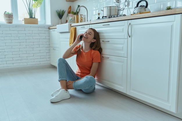 a woman talking on a cell phone in a kitchen