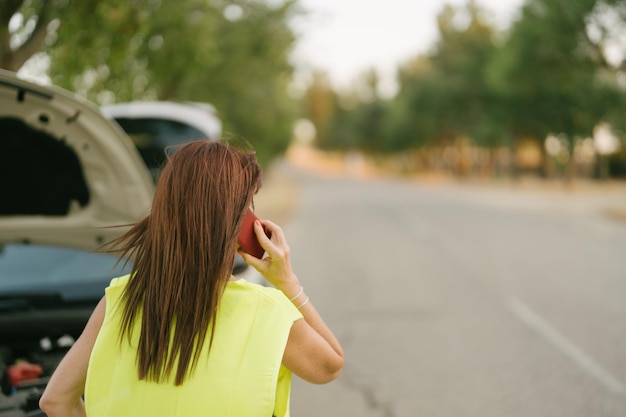 Woman talking on her cell phone while waiting for the tow truck to arrive