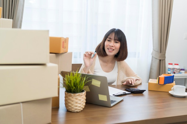 A woman talks on the phone and uses a laptop to confirm orders from customers on the website packs the goods in parcels and sends them through a private courier company