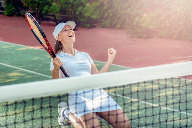 A woman on the tennis court rejoices in scoring a goal and winning a game of the sports game tennis