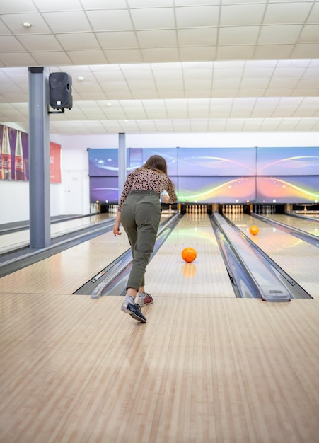 A woman throws a ball into a bowling alley. Paths with balls and pins for bowling.