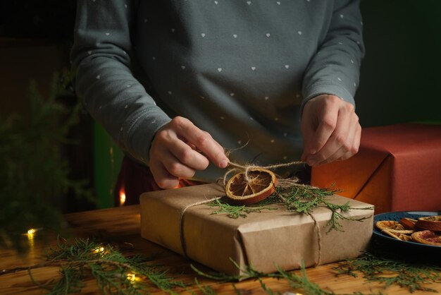 Woman tie a bow on box with Christmas present