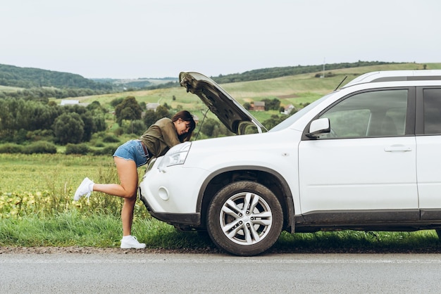 Woman in tight shirts new broken car with opened hood