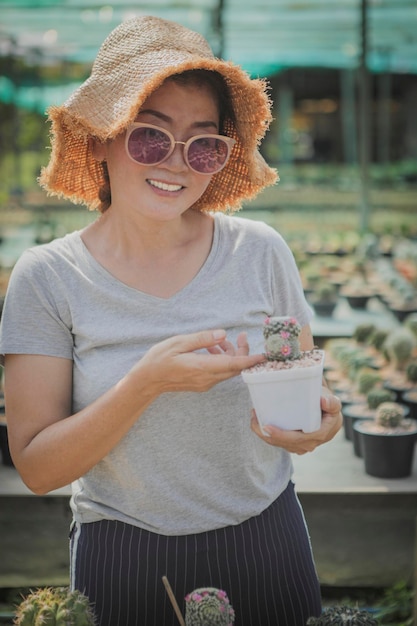 Woman toothy smiling holding cactus pot in hand