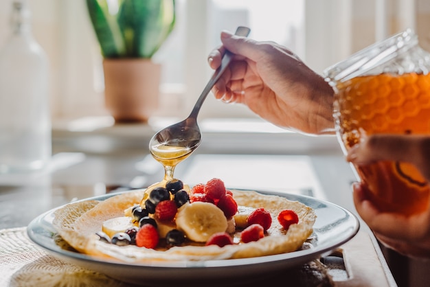 Woman topping thin pancakes with honey