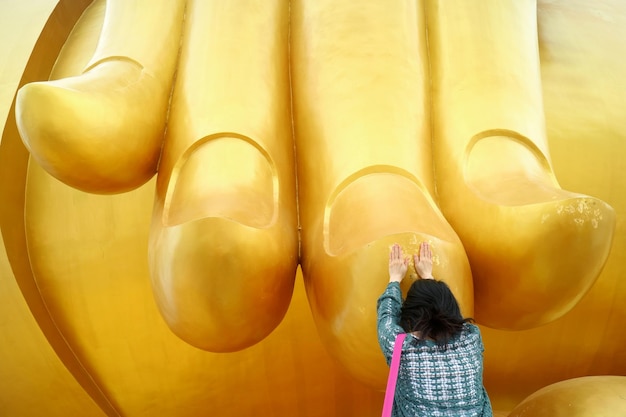 Woman Touching the Finger of the Great Buddha Image for the Blessing at Wat Muang Temple Thailand