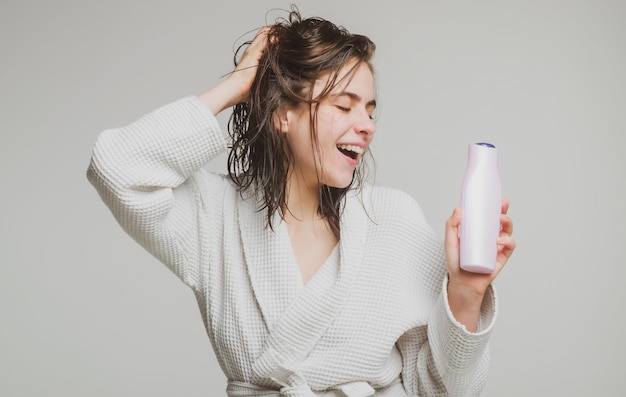 Woman touching her hair woman hold bottle shampoo and conditioner happy young woman with balm bottle