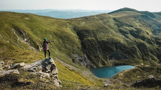 Woman tourist on background of green mountains and lake