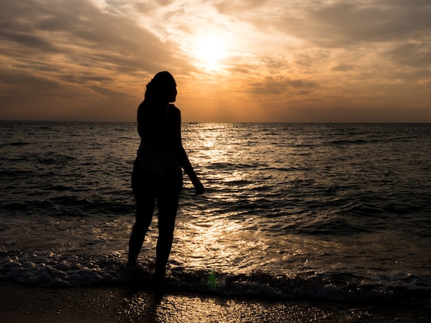 Woman tourist looking at sunset at sea. Relaxation at the sea