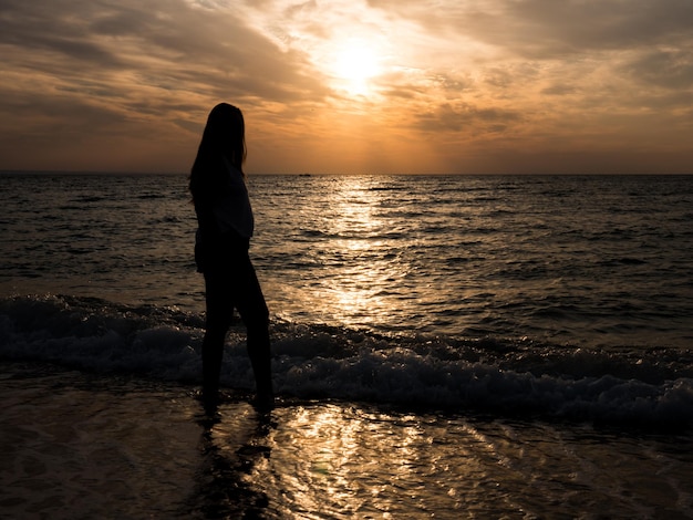 Woman tourist looking at sunset at sea. Relaxation at the sea