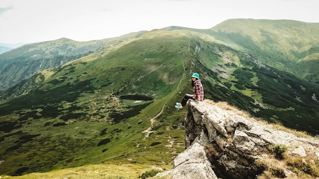 Woman tourist sitting on the background of green mountains and a lake