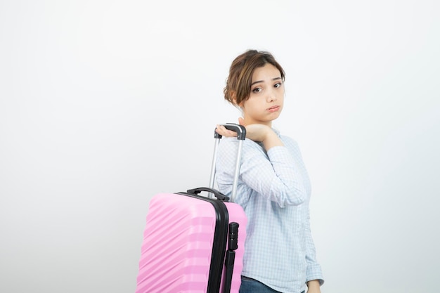 Woman tourist standing and holding pink travel suitcase . High quality photo