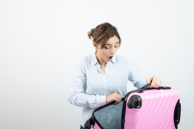 Woman tourist standing and holding pink travel suitcase . High quality photo