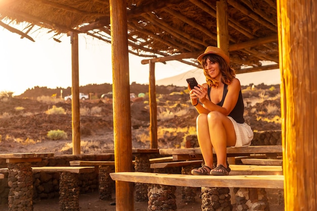 A woman tourist at sunset with the mobile smiling on the beach of Tacoron on El Hierro Canary Islands