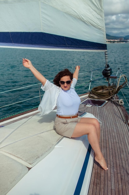 Woman tourist traveler in sunglasses on a summer day on a yacht in the sea