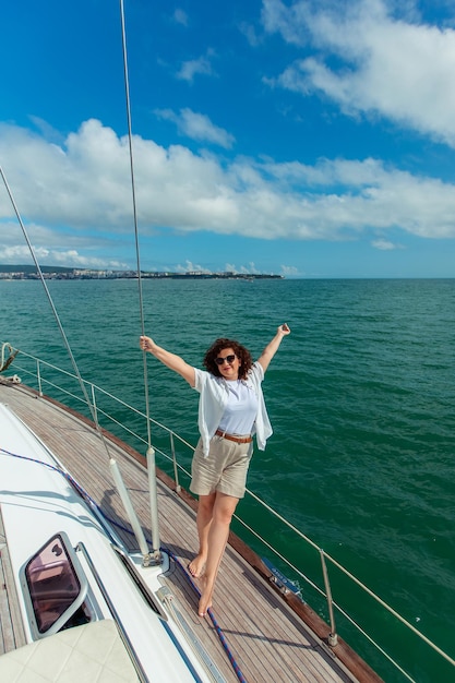 Woman tourist traveler in sunglasses on a summer day on a yacht in the sea