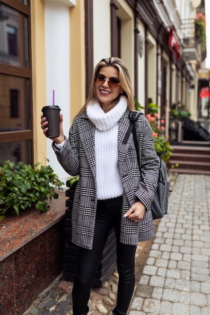 Woman tourist walking around the city in sunglasses with a cup of coffee