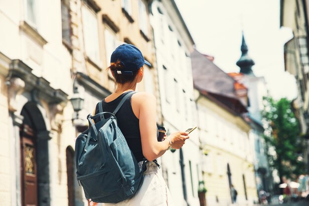 Photo woman tourist with cup of coffee using smart phone on medieval street in old city of ljubljana