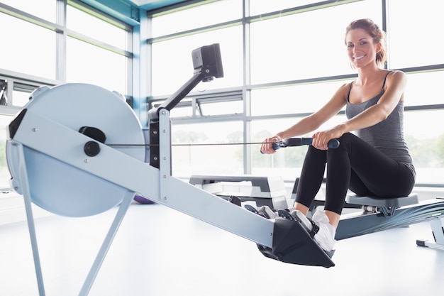 Photo woman training happily on row machine