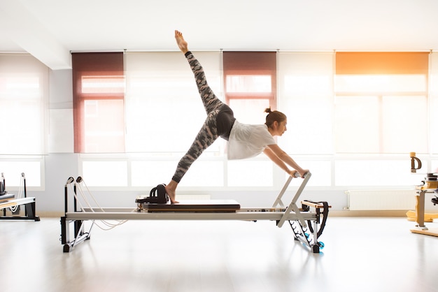 Woman training pilates exercises in covered gym