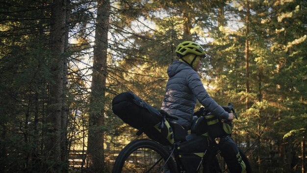 The woman travel on mixed terrain cycle touring with bike bikepacking outdoor The traveler journey with bicycle bags Stylish bikepacking bike sportswear in green black colors Magic forest park