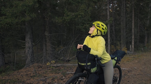 The woman travel on mixed terrain cycle touring with bike bikepacking outdoor The traveler journey with bicycle bags Stylish bikepacking bike sportswear in green black colors Magic forest park