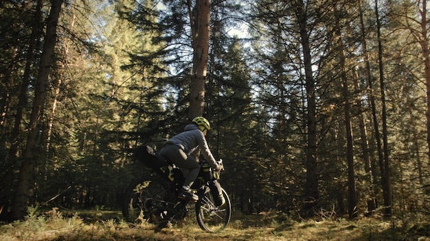 The woman travel on mixed terrain cycle touring with bike bikepacking outdoor The traveler journey with bicycle bags Stylish bikepacking bike sportswear in green black colors Magic forest park