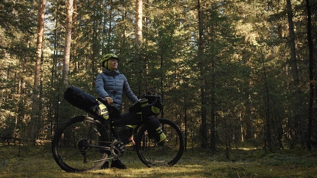 The woman travel on mixed terrain cycle touring with bike bikepacking outdoor The traveler journey with bicycle bags Stylish bikepacking bike sportswear in green black colors Magic forest park