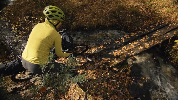 The woman travel on mixed terrain cycle touring with bikepacking The traveler journey with bicycle bags Sportswear in green black colors The trip in magical autumn forest Wooden bridge river