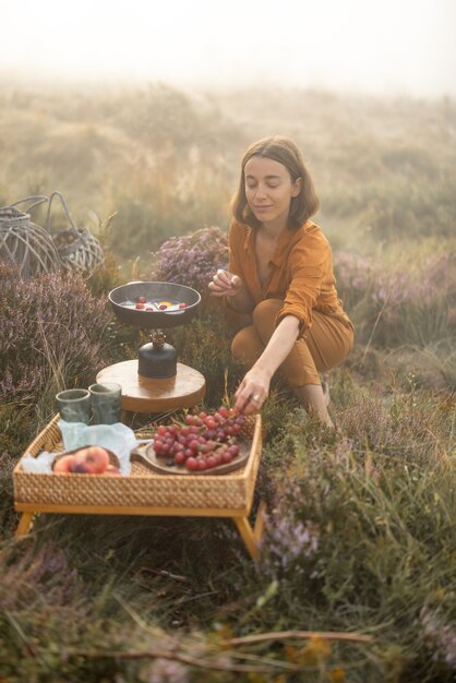 Woman traveler has a beautiful berakfast time with eggs and fruits while traveling in mountains on foggy weather