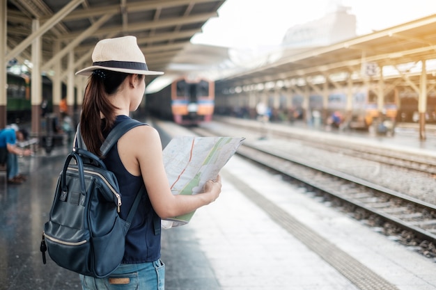 woman traveler looking map while waiting for train at railway platform, Bangkok, Thailad