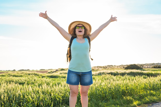 Woman traveler looking sunset at green field