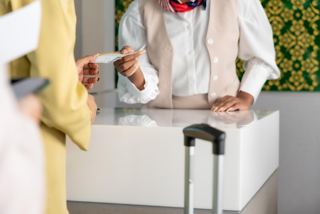 Woman traveler receive boarding pass ticket from female officer at airline check in service counter