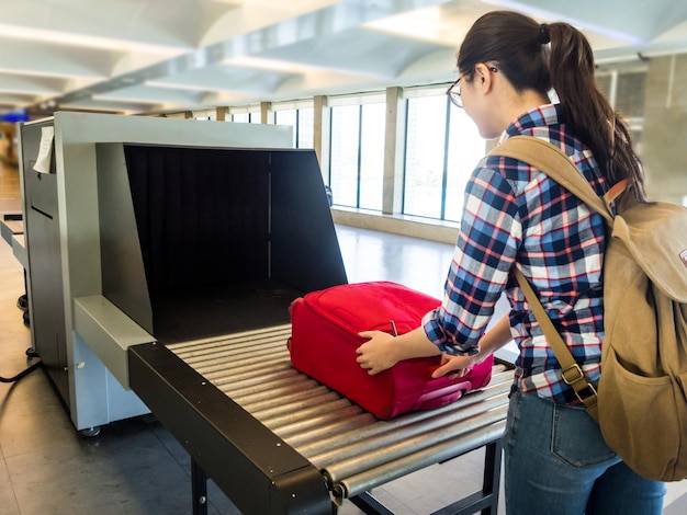 woman traveler selective focus Baggage X-ray machine try to detection metal prevention bad terrorist to attack airplane at the airport before take off.