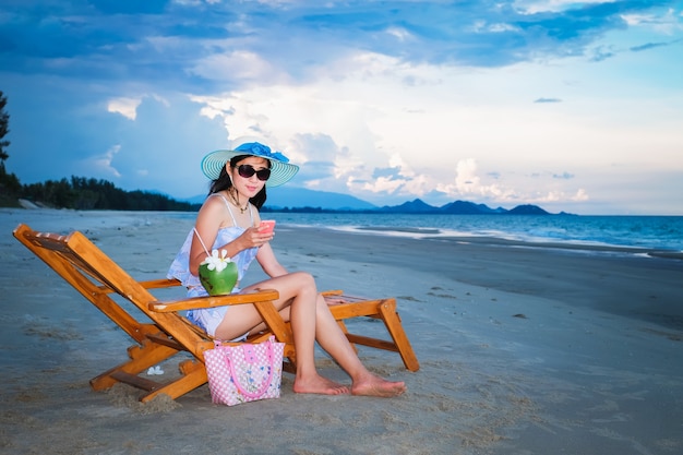 woman traveler in sexy swimming suit sitting on the chair and using mobile phon