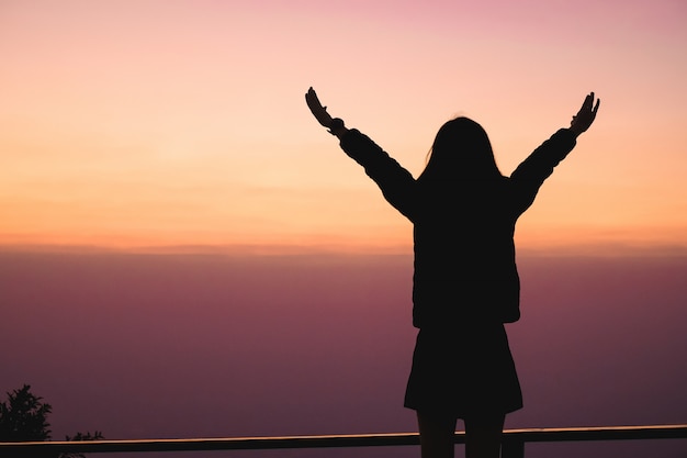 Woman traveler standing on top of the mountain and enjoying for view of nature when the sunset.