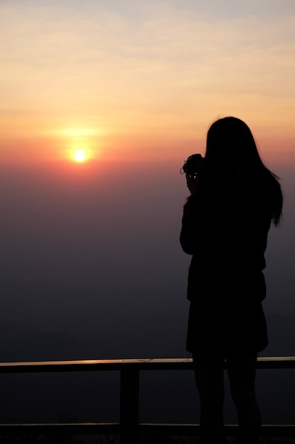 Woman traveler standing on top of the mountain and taking photo view of nature on holiday.