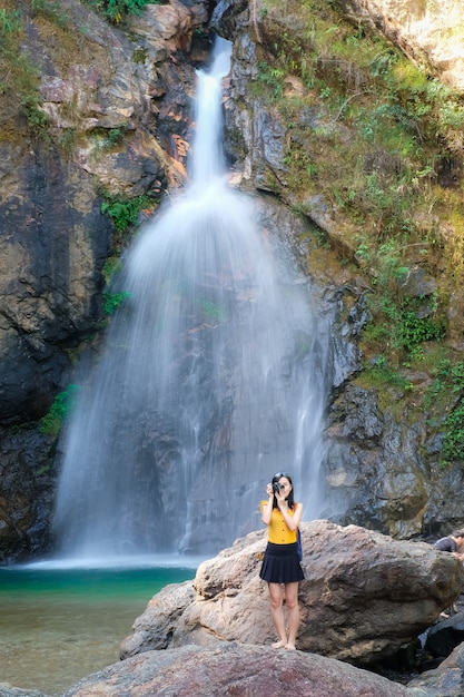 woman traveler take photo waterfall by her camera 