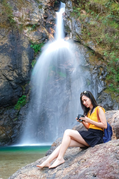 woman traveler take photo waterfall by her camera 