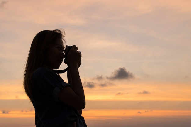 woman traveler taking a picture on the beach at the sunset time.