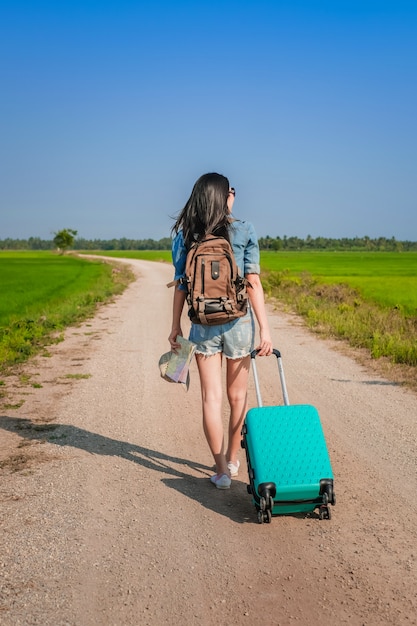 Woman traveler towing baggage and walking on the road. 