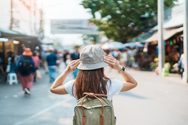 Woman traveler visiting in Bangkok Tourist with backpack and hat sightseeing in Chatuchak Weekend Market landmark and popular attractions in Bangkok Thailand Travel in Southeast Asia concept