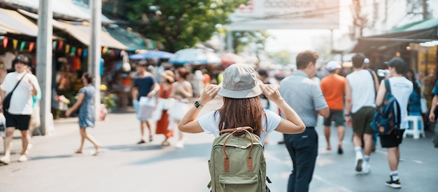 Woman traveler visiting in Bangkok Tourist with backpack and hat sightseeing in Chatuchak Weekend Market landmark and popular attractions in Bangkok Thailand Travel in Southeast Asia concept